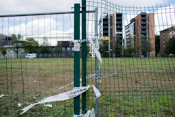 Fence with torn tape beside a flattened lot