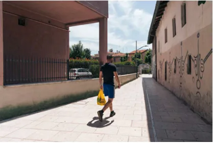 A pedestrian carrying a yellow bag through a covered passage marked with graffiti