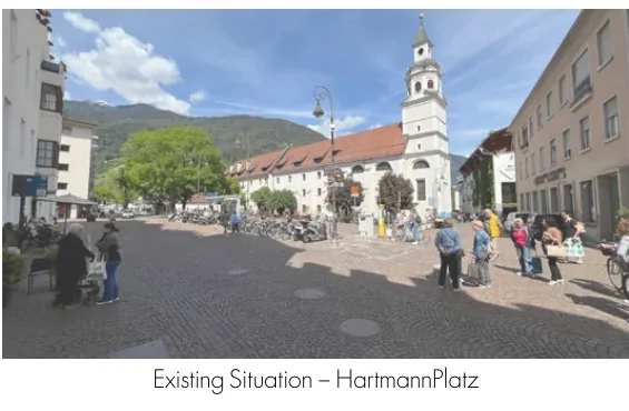 Wide existing view across Hartmannplatz toward the church and surrounding buildings