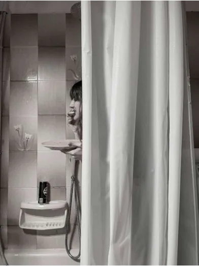 A bathroom sink and partial figure seen past a translucent shower curtain