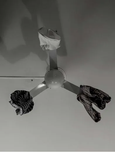 Pieces of laundry suspended from a ceiling light above patterned fabric